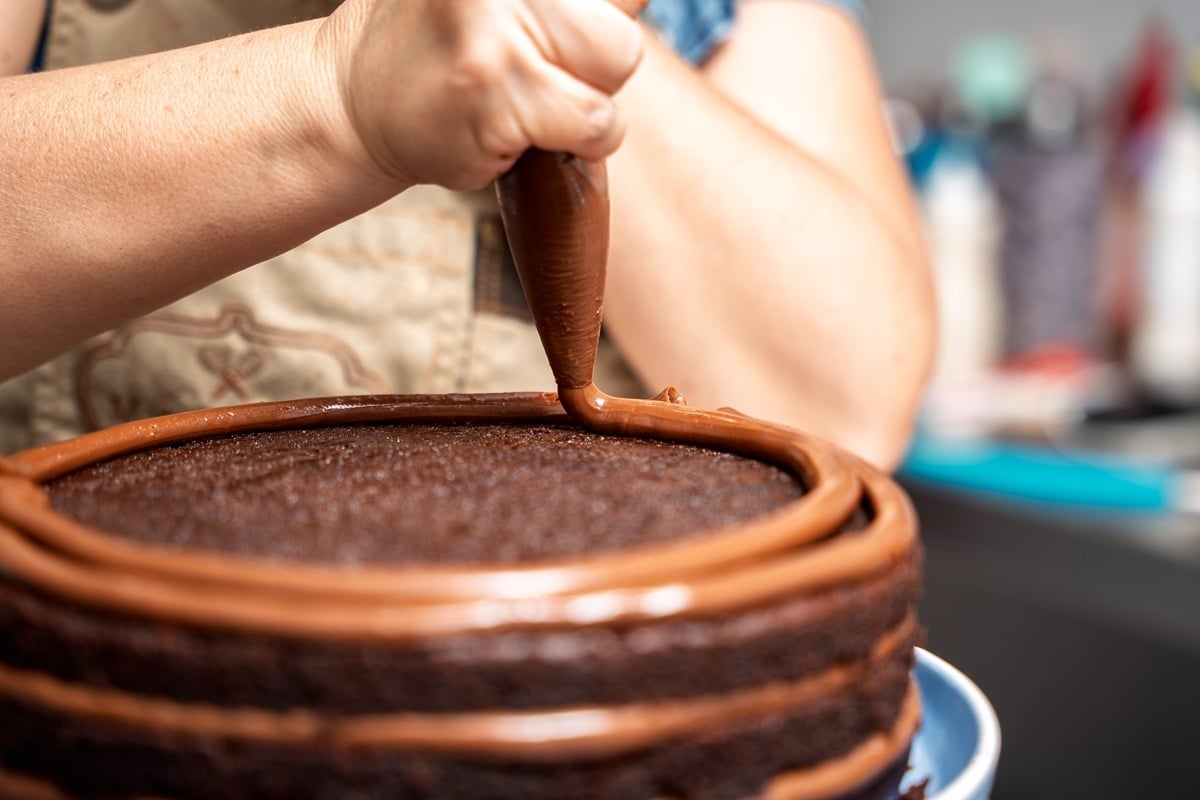 pastry-chef-decorating-chocolate-cake-with-piping-2025-05-16-05-17-35-utc